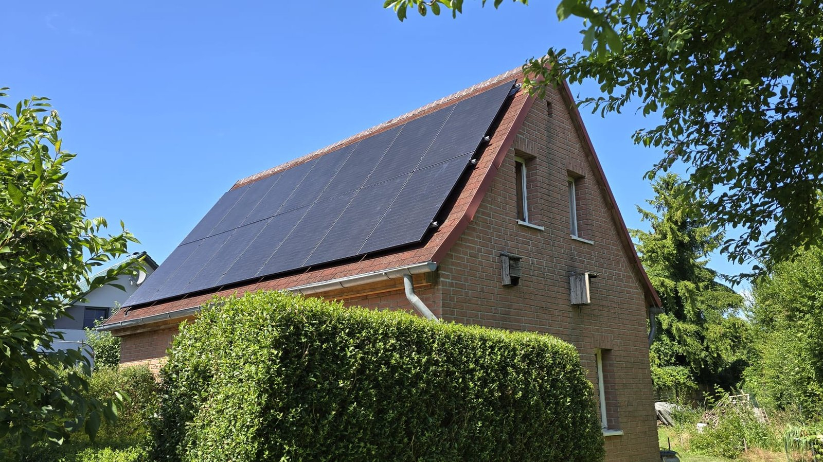 Einfamilienhaus mit Klinkerfassade in der Region Lübeck, Satteldach vollflächig mit schwarzen Photovoltaikmodulen belegt